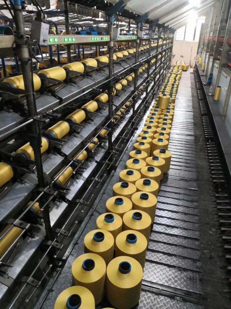 An industrial air-jet texturing machine wrapping elastane around a nylon core.